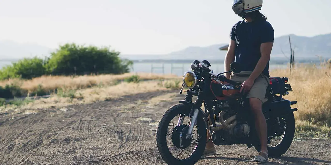 Uomo con casco e abbigliamento leggero, pronto per andare in moto d'estate.