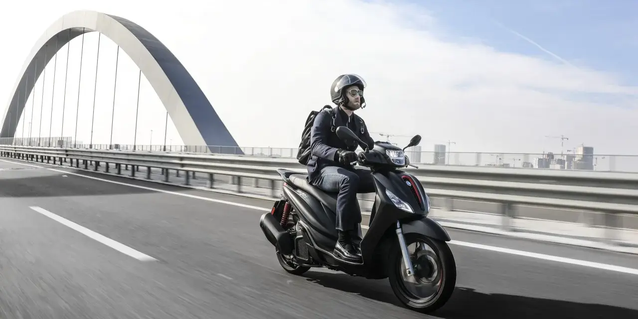 Uomo in moto sfreccia sull'autostrada, con un grande ponte ad arco sullo sfondo. La libertà di viaggiare in moto.