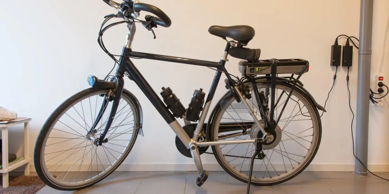 Bici elettrica ferma, la batteria non si carica. Due alimentatori collegati al muro, ma la luce verde sulla batteria è spenta.