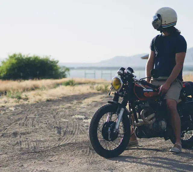 Uomo con casco e abbigliamento leggero, pronto per andare in moto d'estate.