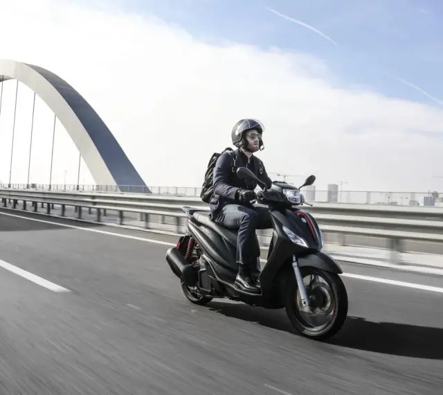 Uomo in moto sfreccia sull'autostrada, con un grande ponte ad arco sullo sfondo. La libertà di viaggiare in moto.