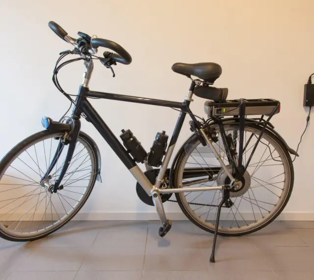 Bici elettrica ferma, la batteria non si carica. Due alimentatori collegati al muro, ma la luce verde sulla batteria è spenta.