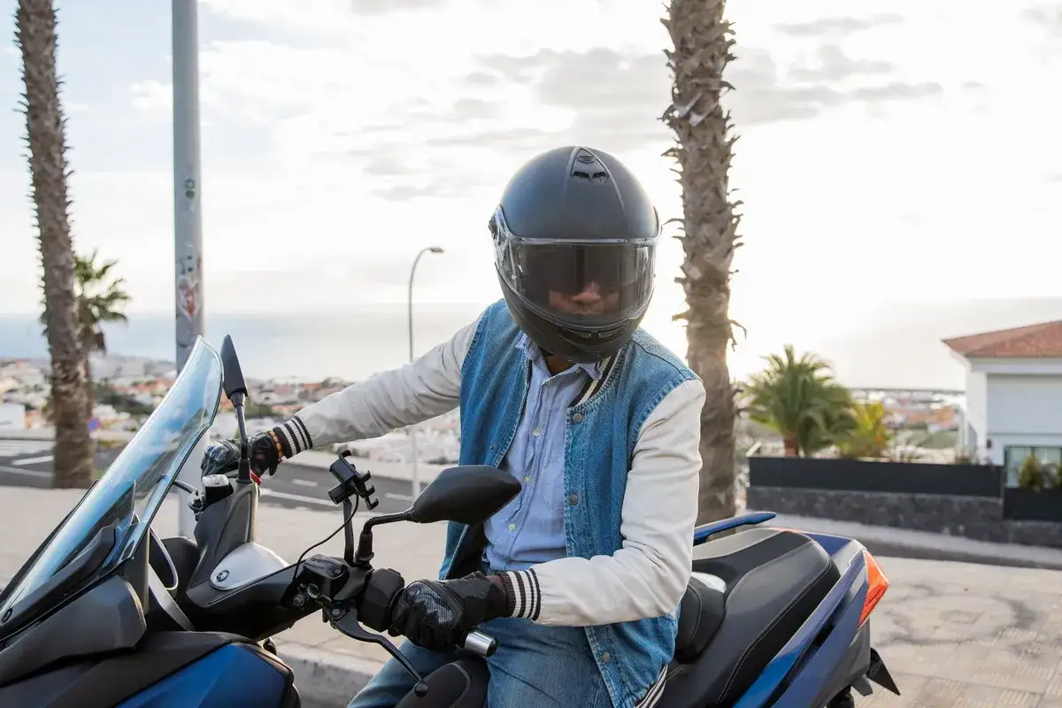 Uomo in moto con casco e giacca di jeans, pronto per un giro estivo. Ecco come vestirsi per andare in moto d'estate: leggero ma protetto.