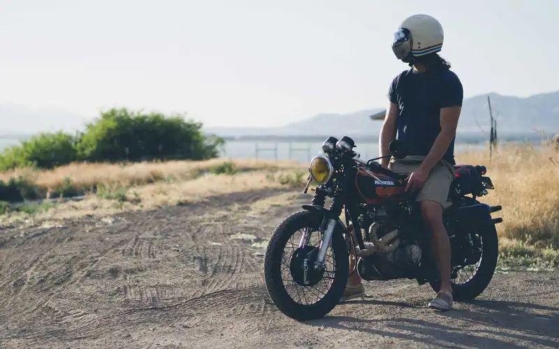 Uomo con casco e abbigliamento leggero, pronto per andare in moto d'estate.