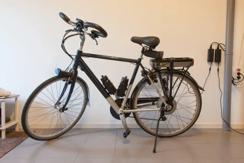 Bici elettrica ferma, la batteria non si carica. Due alimentatori collegati al muro, ma la luce verde sulla batteria è spenta.